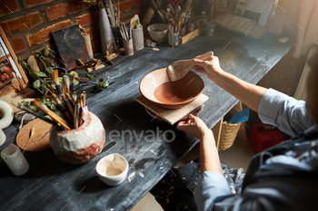 Ceramic artist hands painting clay bowl in workshop / Photodune, Misc