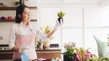 Happy gardener woman holding flowerpot in the room. / Photodune, Misc