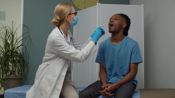 Female Doctor Checking Young Adult Man for Sore Throat Indoors