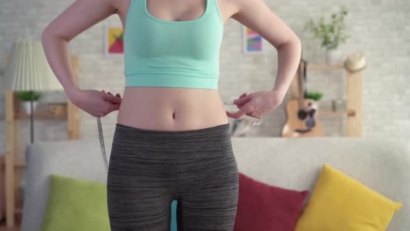 Expressive Joyful Young Woman in Sportswear Uses Measuring Tapeclose Up