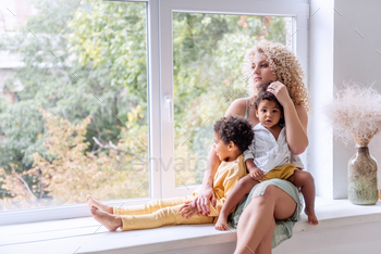 Young blond Caucasian woman hugging African American children, daughter and son. / Photodune, Misc