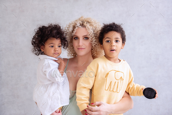 Young blond Caucasian woman holds in her arms, hugging, African American children, daughter and son / Photodune, Misc
