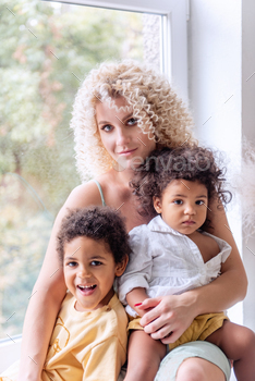 Young blond Caucasian woman hugging African American children, daughter and son. / Photodune, Misc