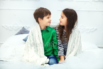 Little friends, a boy and a girl sitting on the bed. The concept of love and Valentine's Day / Photodune, Misc