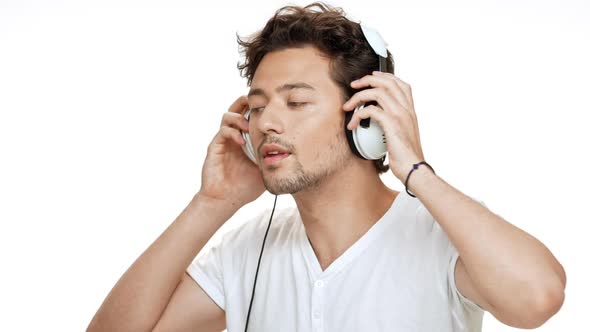 Young Handsome Man Smiling Listening Music in Headphones Dancing Over White Background