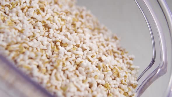 Popped amaranth seeds moving in slow motion in a kitchen plastic container