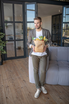 Young fair-haired man with a package of food in the kitchen / Photodune, Misc