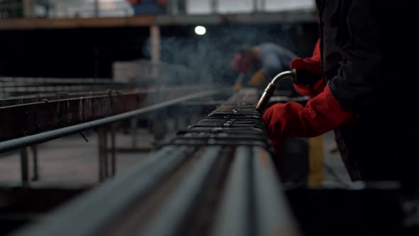 A welder in a metal shop workshop is cooking steel parts