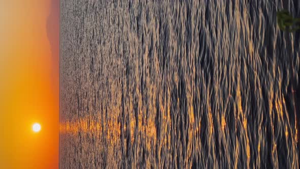 The Vertical Footage of Picturesque Sunset Against the Backdrop of Mountains From a Yacht in Motion