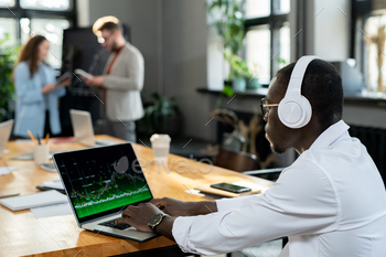 African male economist in headphones using laptop / Photodune, Misc