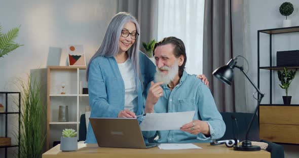 Male and Female Pensioners Talking at the Table and Discussing Report About Family Costs