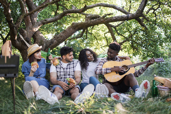 Carefree diverse people playing guitar during picnic at park / Photodune, Misc