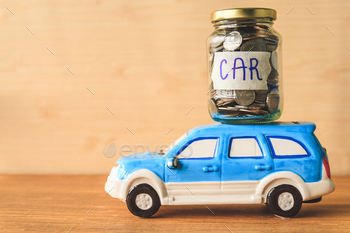 Coins in glass jar with car label and car toy on wooden table. Financial Concept / Photodune, Misc