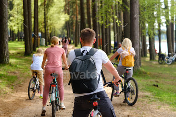 A group of cyclists with backpacks ride bicycles on a forest road enjoying nature / Photodune, Misc