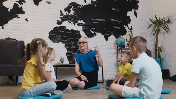 Group of Kids Sitting on the Floor in Circle Around the Teacher