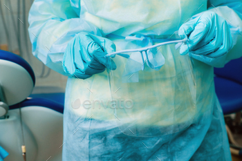 close up of a dentist's hands holding a protective plastic screen in his office / Photodune, Misc