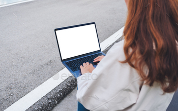 woman using and typing on laptop computer with blank white desktop screen in the outdoors / Photodune, Misc