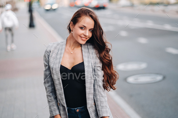 a girl in a jacket and long hair walks through the old city.A beautiful girl smiles.Girl on the road / Photodune, Misc