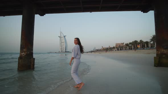 Attractive Young Woman Walking on Sand Beach in Dubai in Front of Burj Al Arab Hotel