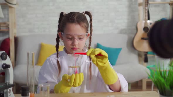 Teen Blogger in a White Coat and Glasses in the Laboratory Mixes the Reagents