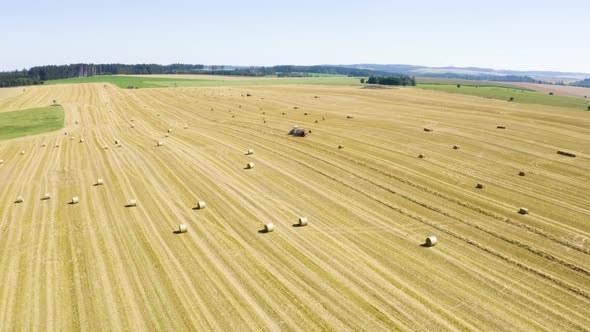 Aerial Drone Shot  a Field with Tractors and Hay Bales in a Rural Area on a Sunny Day