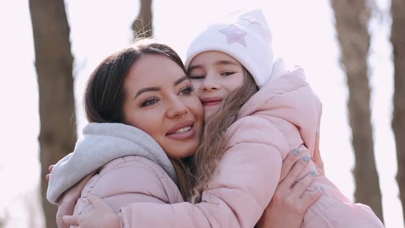 Beautiful Mother Is Walking with a Cute Daughter in a Park