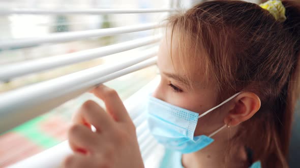 Little Girl in a Protective Mask Sits in Quarantine at Home