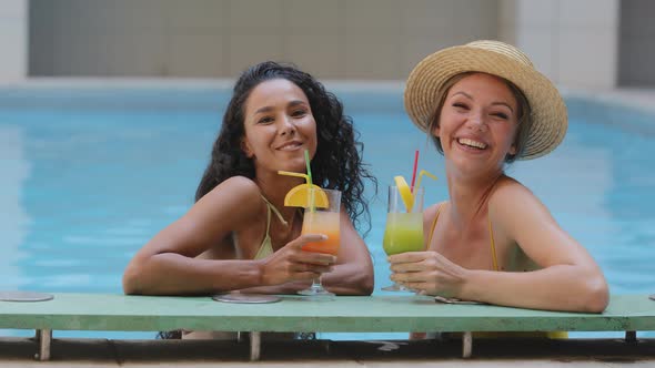 Two Happy Funny Multiracial Girlfriends Holding Exotic Nonalcoholic Ice Fruit Cocktails Making Cheer