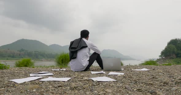 Businessman Near River Among The Scattered Papers