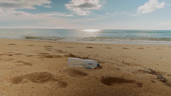 Plastic bottle on the beach, slow rolling waves in the distance.