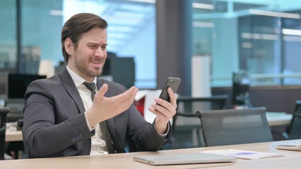 Upset Businessman Reacting to Loss on Smartphone