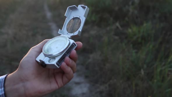 Man Uses a Compass In The Woods At Sunset