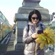 A Middleaged Woman a Brunette Caucasian Race with a Bouquet of Yellow Leaves Walks Across the Bridge - VideoHive Item for Sale