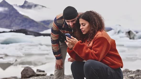 Travelers Looking at the Photos on the Phone and Glacier Field As Background