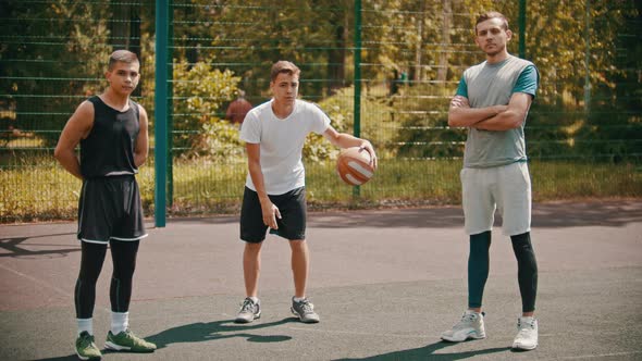 Three Sportsmens Standing on the Basketball Court Outdoors and Looking in the Camera - One Sportsman