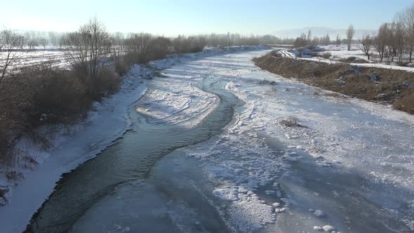 Water Canal Flowing Under Frozen Ice Sheets in Sunny Winter