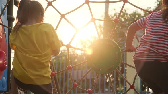 Happy two little girls climbing on rope mesh at playground. Active little girls on playground