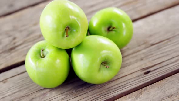 Green apples arranged on wooden plank