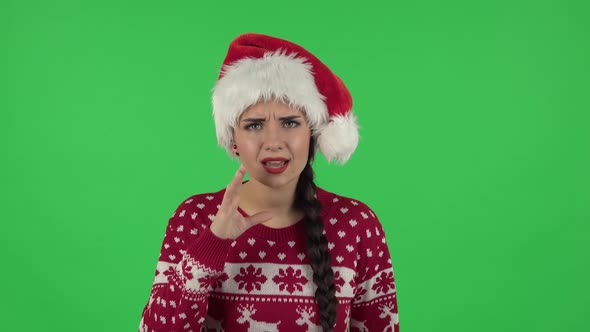 Portrait of Sweety Girl in Santa Claus Hat Is Negatively Screaming Calling Someone. Green Screen