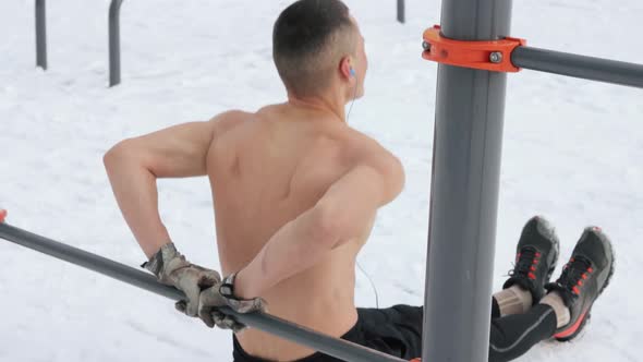 Muscular man training topless on sports field in winter