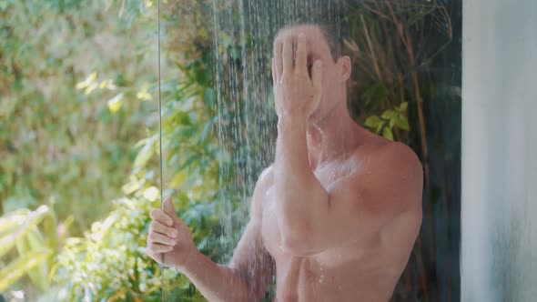 Sexy Man with Muscular Body Takes Shower Tropical Greenery on Background