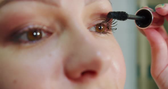 Close Up of Attractive Woman Putting on Makeup with Brush Adding Mascara on Eye