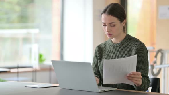 Young Woman with Laptop Working on Documents 