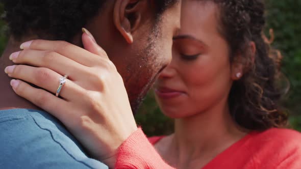 Close up of happy biracial woman with engagement ring on hand hugging to fiance