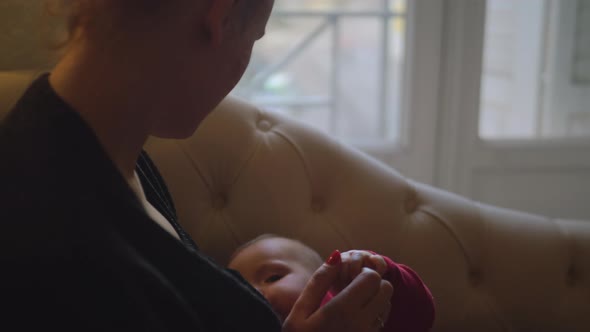 Mother breast-feeds her daughter near window