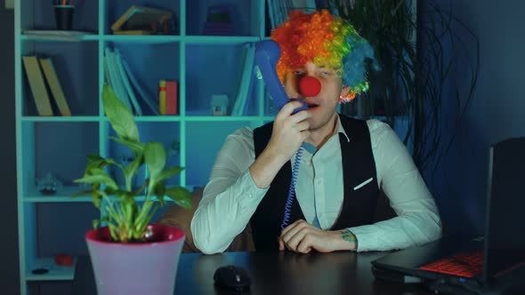 Young Man in Image of Clown Talking Into Phone in Office