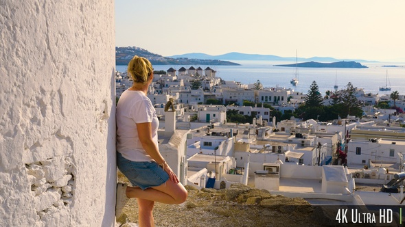 4K Female Tourist Looking at the View of Windmills and Mykonos Town at Sunset, Greece