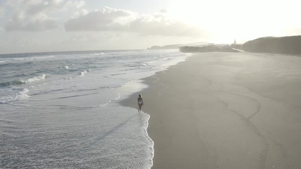 Aerial View of a woman walking on the beach, Praia do Areal, Azores, Portugal.