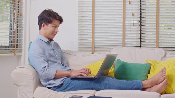 Entrepreneur handsome business asian man wear blue shirt lying on couch working online