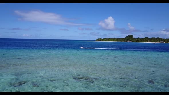 Aerial flying over panorama of tranquil seashore beach time by transparent water and bright sand bac